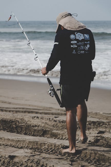 A man fishing barefoot on a beach in Altata, Mexico, with a fishing rod.