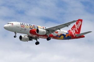 AirAsia aircraft flying through the sky with vibrant livery promoting Bali travel.