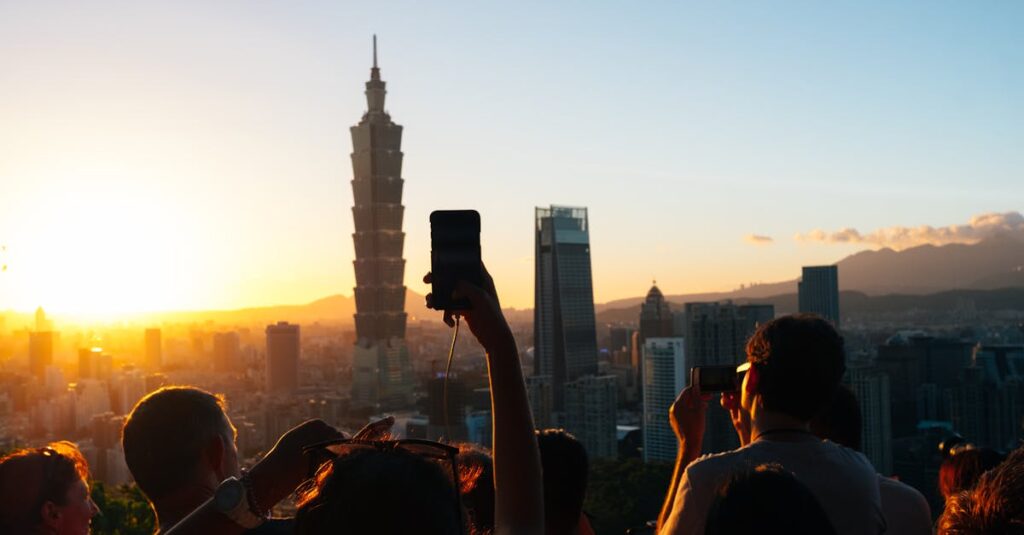 Dramatic sunset over Taipei with silhouette of people photographing Taipei 101.