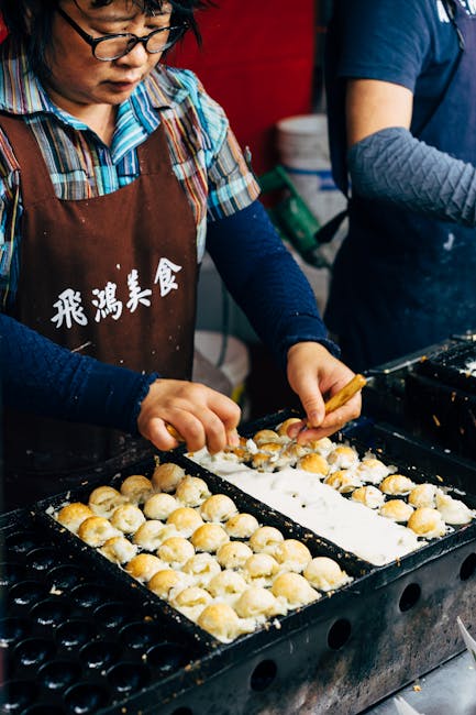 Street vendor cooking takoyaki in Taipei, Taiwan at a food market. Captured close-up of the preparation process.