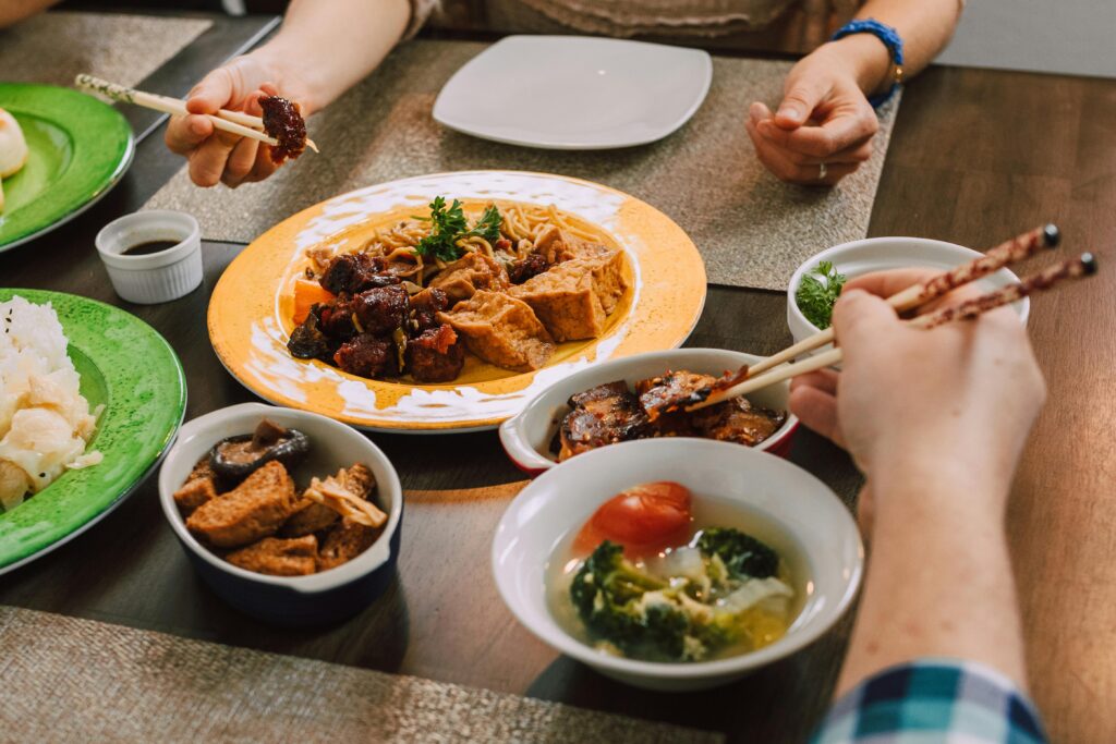 A delicious spread of Asian dishes including tofu, noodles, and vegetables shared at a family dinner table.