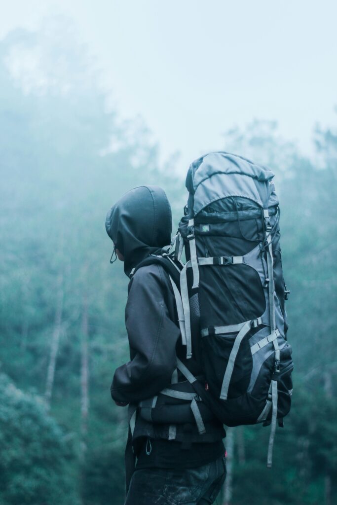 Solo hiker with large backpack in a misty forest, exploring nature's serene beauty.