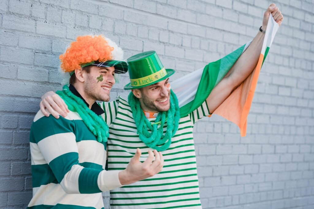 Two men celebrating Saint Patrick's Day with festive attire and Irish flag outside.